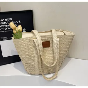 Détail du sac cabas en paille tressée avec écusson en cuir brun et décor de tulipes