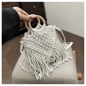Close-up of bohemian hand-woven macrame bag with tassel details and round wooden handles