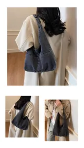 Detailed view of black washed denim hobo bag with vintage texture and wide shoulder strap