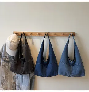 Close-up of hobo denim shoulder bags in three colors hanging on wooden hooks