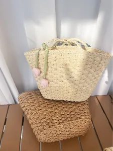 Détail du sac cabas beige tressé avec ruban vert et breloques de tulipes roses