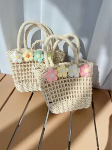 Close-up of handmade woven straw tote bags with colorful knitted floral decorations
