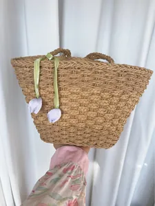 Détail du sac cabas en paille tressée avec breloque tulipe violette et ruban vert doux