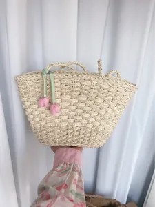Détail d'un sac à main tressé avec rubans verts et breloques tulipes en tissu
