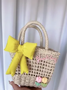 Detail of woven straw bag with yellow satin bow, pink tulip charms and Goodday embroidery