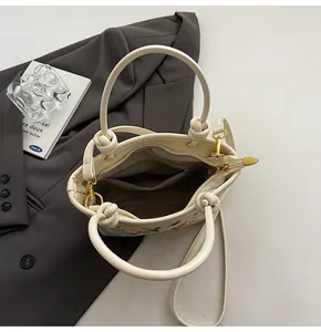 Détail du sac seau crème montrant la poche zippée et la broderie florale élégante