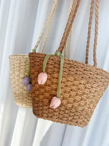 Détail de sacs cabas tissés avec breloques tulipes en couleurs beige et marron