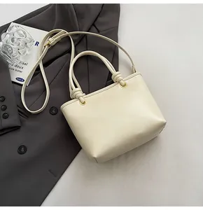 Gros plan du sac seau crème avec détail de nœud unique et bandoulière réglable
