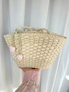 Détail du sac en paille tressé avec bord festonné, ruban et breloques tulipes