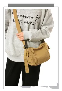 Khaki canvas messenger bag worn across the body with adjustable wide shoulder strap
