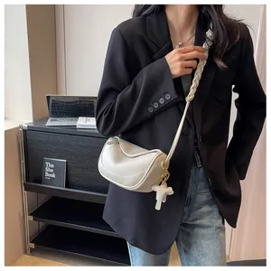 Chic cream dumpling crossbody bag in lychee leather featuring a cute elephant charm