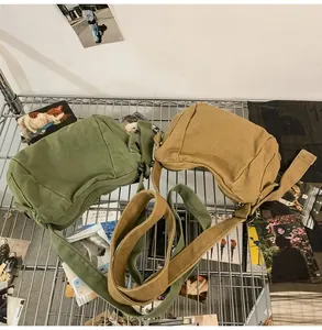 Close-up of canvas shoulder bags in khaki and army green on a metal rack