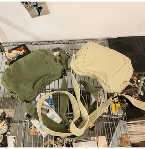 Canvas messenger bags in army green and beige shown on a shelf with adjustable straps