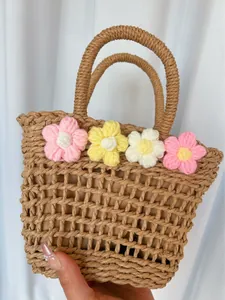 Detail of hand-woven straw bag featuring colorful crochet flowers and inner lining