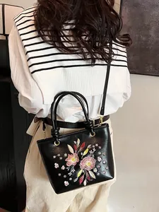 Sac seau élégant en cuir noir avec broderie florale et double bandoulière amovible