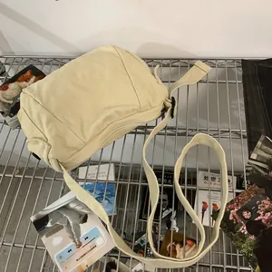 Detail of cream canvas messenger bag with adjustable strap on a minimalist metal rack