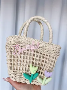 Detail of woven straw bag featuring pink 'Beautiful' embroidery and tulip floral appliques