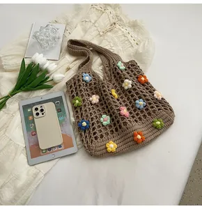 Dettaglio dei motivi floreali all'uncinetto 3D su una borsa tote in maglia marrone