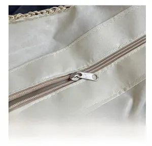 Détail de la fermeture éclair en métal argenté et de la doublure textile du sac en paille