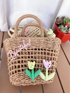 Detailed close-up of woven straw handbag with Beautiful embroidery and tulip charms