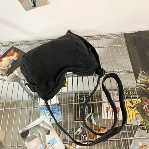 Top view of a black canvas crossbody bag with adjustable strap on a creative art background