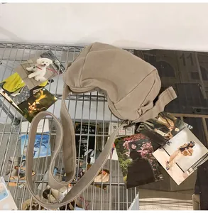 Top-down view of khaki canvas messenger bag on metal grid with creative magazine decor