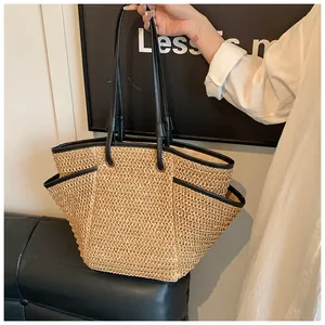 Détail du sac cabas en paille tressée avec bordure en cuir noir et poches latérales