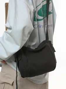 Minimalist black canvas messenger bag for men and women featuring adjustable crossbody strap