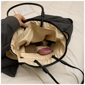 Détail intérieur du grand sac fourre-tout noir avec doublure beige et poche zippée
