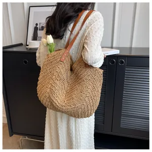Détail du sac cabas en paille tressée avec anses en cuir marron et texture en V