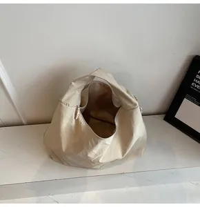 Detail of a beige minimalist hobo bag with soft pleated canvas on marble surface