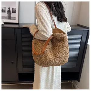 Détail du tissage ajouré ondulé et des anses en cuir marron du sac cabas en paille