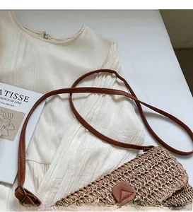 Detail van stro schoudertas met verstelbare leren riem en driehoekige patch