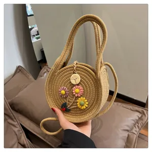 Détail du sac rond en paille avec fleurs tricotées, breloque coccinelle et bouton en bois