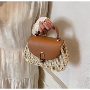Detail of woven straw handbag featuring a brown leather flap and golden twist lock closure