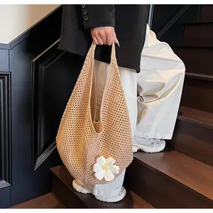 Detail of hollow woven beach tote bag featuring a 3D white knitted flower accent