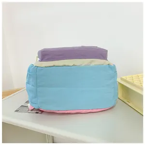 Detail of color-block nylon backpack featuring purple and beige patchwork with side pocket