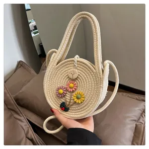 Détail d'un sac rond en paille tressée avec fleurs 3D et fermoir en bouton de bois