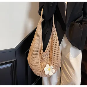 Detail of hand-woven beige tote bag with white floral accent and soft knit texture