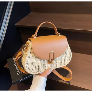 Detail of vintage woven straw handbag with brown leather flap and gold metal buckle