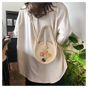 Vue détaillée d'un sac en paille tressée orné de fleurs 3D et d'un charm coccinelle