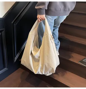 Close-up of beige nylon tote bag showing soft crinkled texture and sleek side zipper detail