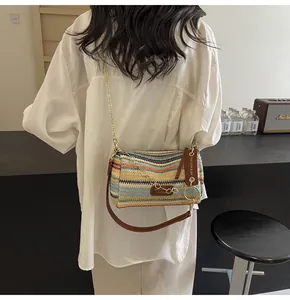 Detailed back view of a rainbow striped cylinder straw bag with gold chain strap on model