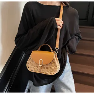 Detail of woven straw handbag with brown leather flap and golden U-shaped metal buckle