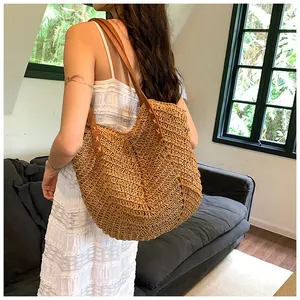 Détail du sac cabas en paille tissée avec bandoulière en cuir marron et coutures soignées