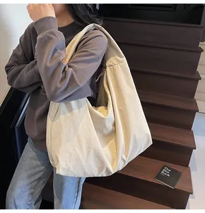 Close-up of off-white oversized hobo bag on shoulder against dark wooden stairs