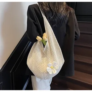 Detail of white crochet tote bag with handmade flower accent and spacious mesh weave