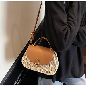 Detail of woven straw handbag with brown leather flap and gold buckle on a model
