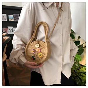 Détail d'un sac rond en paille avec fleurs 3D et fermeture par bouton en bois rustique