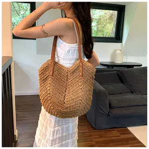 Détail d'un sac cabas en paille tressée avec poignée en cuir et couture en croix